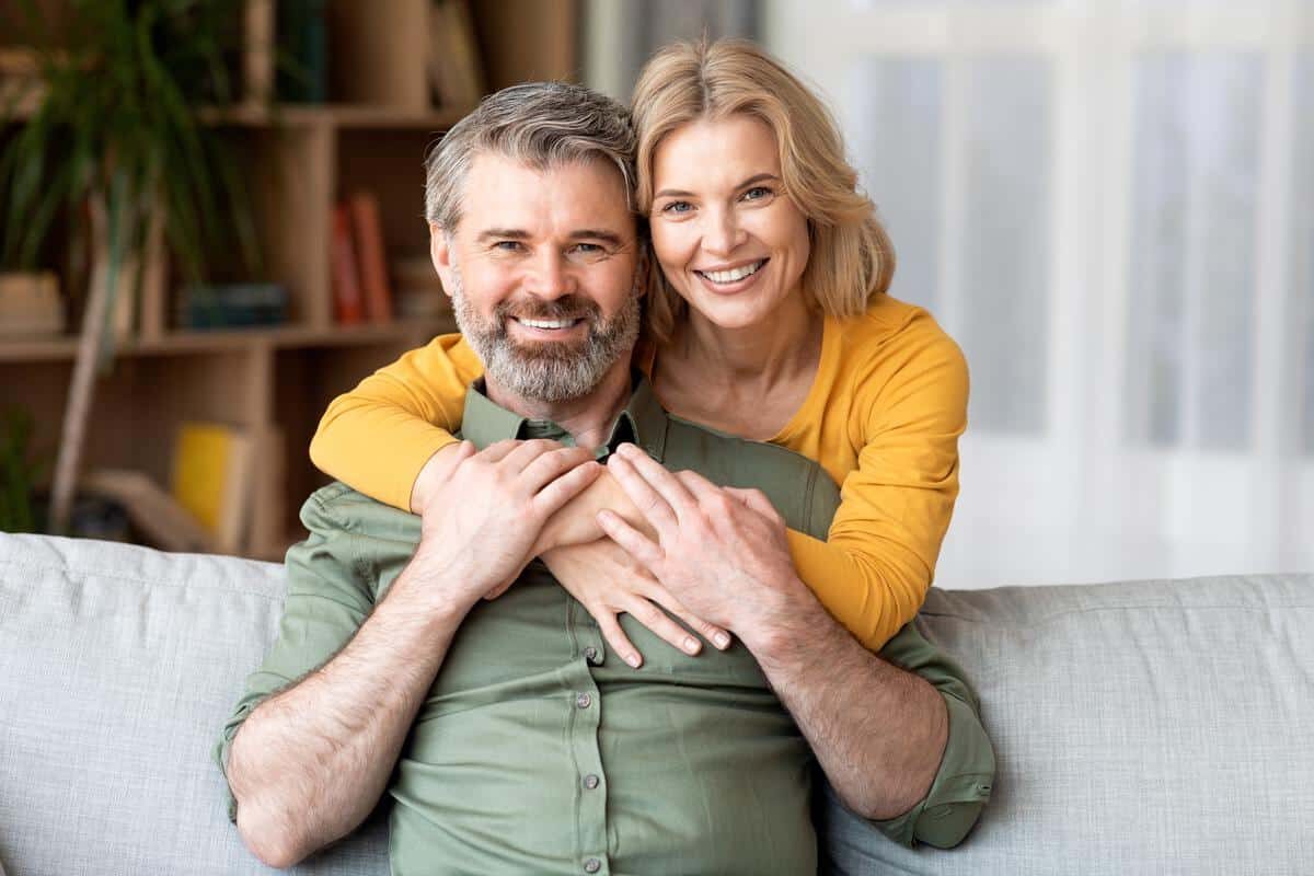 Smiling-couple-indoor-home Happy smiling couple middle aged couch