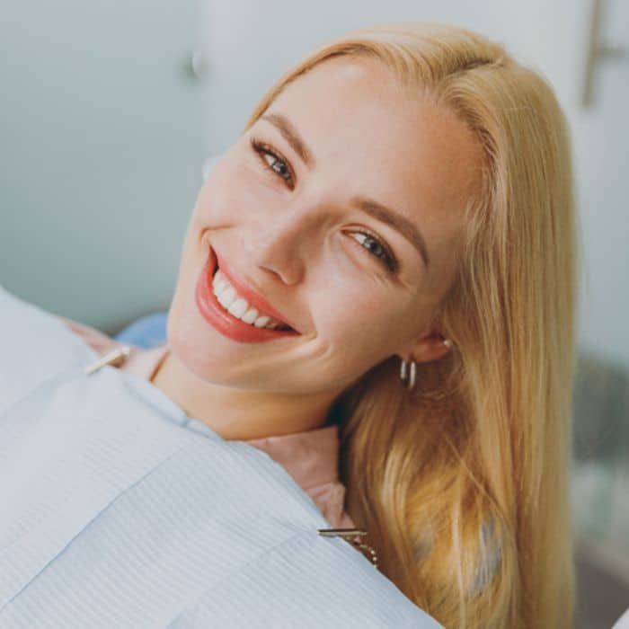 Smiling-patient-woman-dental-treatment-beautiful-smile Blonde lady holding head up at dentist perfect teeth