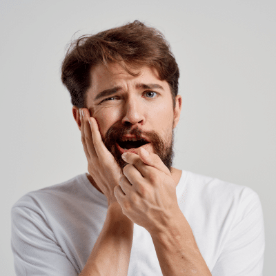 Preventing common dental problems 1 Man holding jowl, in pain, representing common dental problems