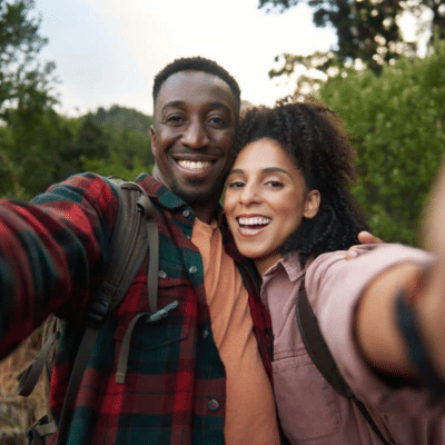 Restoring the function and beauty of your smile with implant restorations 7 Young couple smiling while taking a selfie on a hike, representing implant restoration